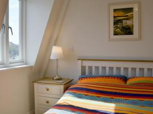 a bedroom with a bed and a lamp and a window at Sandcastles in Swanage