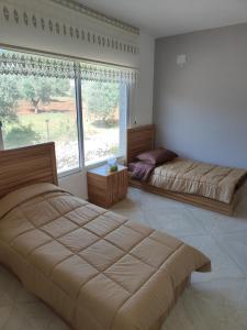 ein Schlafzimmer mit zwei Betten und einem großen Fenster in der Unterkunft Chalets in the middle of Ajloun forests شاليه و مزرعة في وسط غابات عجلون in Adschlun + 28 Fotos