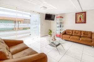 sala de estar con 2 sofás de cuero marrón y TV en OYO Hotel Familiar Tollan en Cholula