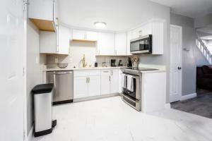 uma cozinha com armários brancos e electrodomésticos de aço inoxidável em All New! Convenient Location! Sleeps 8 em Denver