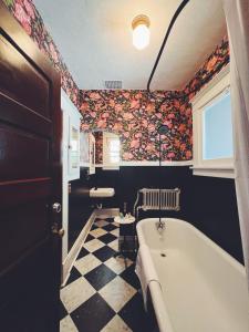 La salle de bains est pourvue d'une baignoire et de papier peint floral. dans l'établissement Marianna Stoltz House, à Spokane
