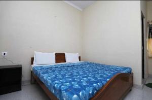 a bedroom with a bed with a blue blanket on it at POP Hotel Amrit Castle 2 in Morādābād
