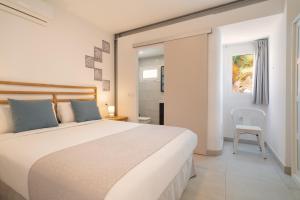a bedroom with a large white bed and a chair at Sabbia Suites Noa Boutique Apartments in Puerto del Carmen