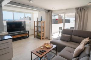 a living room with a couch and a flat screen tv at Sabbia Suites Noa Boutique Apartments in Puerto del Carmen