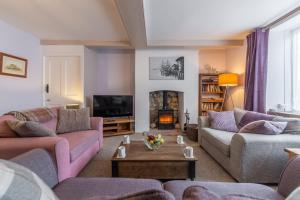 a living room with two couches and a fireplace at Greyhound Cottage in Sculthorpe
