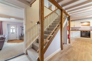 a staircase in a living room with wooden beams at Greyhound Cottage in Sculthorpe