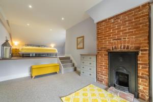 a living room with a brick fireplace and a bed at Greyhound Cottage in Sculthorpe