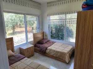 ein Schlafzimmer mit einem Bett und einem großen Fenster in der Unterkunft Chalets in the middle of Ajloun forests شاليه و مزرعة في وسط غابات عجلون in Adschlun