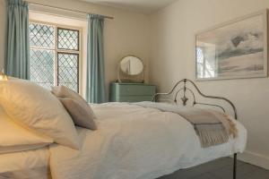 a bedroom with a bed with white sheets and a mirror at Willow Cottage 2 in North Creake