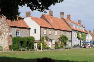 a row of houses with red roofs and green grass at Willow Cottage 2 in North Creake