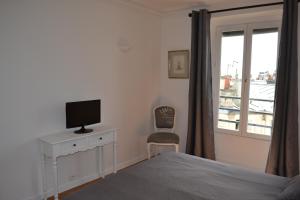 a bedroom with a bed and a television and a window at Appartement moulin rouge II in Paris