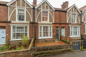 a brick house with white windows and a driveway at Tide Cottage O in Overstrand