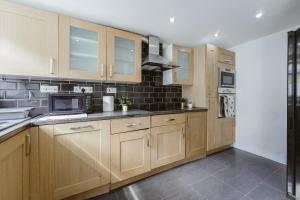 a kitchen with wooden cabinets and a microwave at Great Rooms in Stepney Green Station - 12 in London