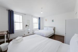 a bedroom with two beds and a desk and two windows at Great Rooms in Stepney Green Station - 12 in London