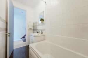 a white bathroom with a tub and a sink at Great Rooms in Stepney Green Station - 12 in London