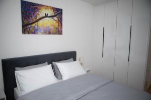 a bedroom with a bed with a painting above it at APARTMAN SONJA in Trebinje