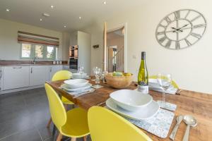 ein Esszimmer mit einem Holztisch mit gelben Stühlen und einer Uhr in der Unterkunft Samphire House in Bodham