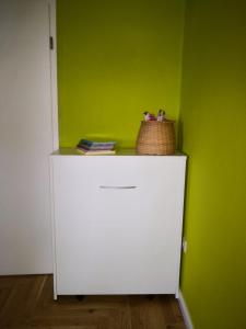 a white cabinet in a green room with a basket on top at Anna in Anklam