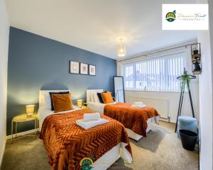 a bedroom with two beds and a blue wall at Low Rate 3 Bedroom House Very Close To Coventry Building Society Arena aka Ricoh Arena, Sleeps 8, Free Driveway Parking and Free Wi-Fi, with Garden - RRN in Exhall