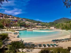 a swimming pool with chairs and a beach at Les Restanques rez jardin 2063 in Grimaud