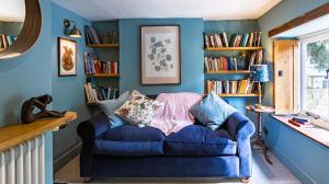 ein blaues Wohnzimmer mit einem blauen Stuhl und Bücherregalen in der Unterkunft Cedar Cottage in Chipping Norton