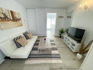 uma sala de estar com um sofá branco e uma televisão em Our Charming House em Portimão