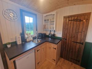 a kitchen with a sink and a wooden door at Cwtch Glamping Shepherds Huts in Abergavenny