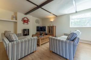 a living room with two chairs and a tv at Crabpot Cottage in West Runton