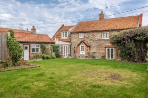 an exterior view of a brick house with a yard at Barn Cottage 6 in Salthouse