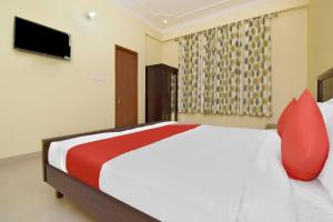 1 dormitorio con 1 cama con almohadas rojas y TV en Collection O Hotel Albert en Jaipur