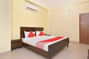 1 dormitorio con 1 cama grande con almohadas rojas en Collection O Hotel Albert en Jaipur