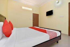 Collection O Hotel Albert في جايبور: غرفة نوم بسرير ومخدات حمراء وتلفزيون