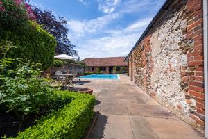 a garden with a swimming pool next to a brick wall at Ivy Farm in Grimston