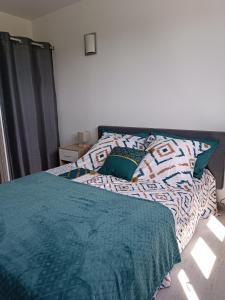 uma cama com um edredão verde e almofadas em Chalet Miquéou Gers em Marseillan