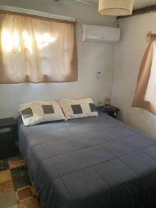 1 dormitorio con 1 cama azul y 2 almohadas en Depto a 6 cuadras de la playa y 5 min. casco histórico, en Colonia del Sacramento