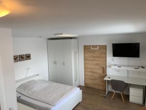 Dormitorio con cama, escritorio y TV en Frundsberg-Apartment, en Mindelheim