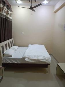 a bedroom with a white bed with a ceiling fan at OYO IAE566 Neelkanth Hotel in Rewāri