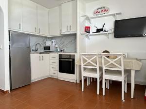 Casa Peña en Son Bou في سون بو: مطبخ مع دواليب بيضاء وطاولة وكراسي