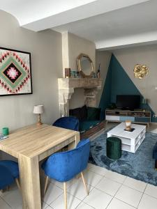 a living room with a wooden table and blue chairs at La maison des lauriers in Valognes