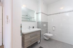 La salle de bains blanche est pourvue d'un lavabo et de toilettes. dans l'établissement Villa Piramida, à Trogir