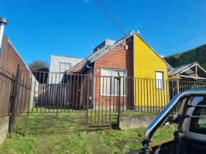 una casa amarilla con una valla delante de ella en Casa completa en Castro