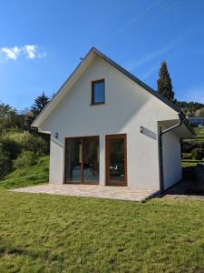 une maison blanche avec des portes en verre sur une pelouse dans l'établissement Chaty Vážka, à Štiavnické Bane