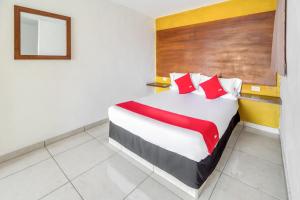 a bedroom with a bed with red and white pillows at OYO Hotel Familiar Tollan in Cholula