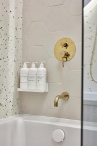 a bathroom with a shower with three bottles of soap at ŻOLI STORK APARTMENTS - Hubnera 5 in Warsaw