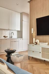 a kitchen with white cabinets and a tv on a wall at ŻOLI STORK APARTMENTS - Hubnera 5 in Warsaw