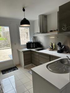 a kitchen with a sink and a counter top at La maison des lauriers in Valognes