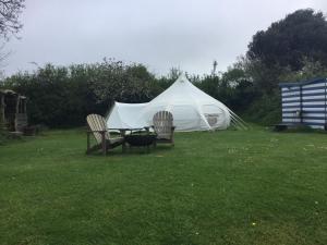 a tent with two chairs and a table in the grass at Horsemans Stargazing Tent in Kingsbridge