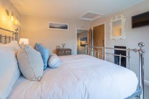 1 dormitorio con 1 cama blanca grande con almohadas azules en Pond Cottage, en Docking
