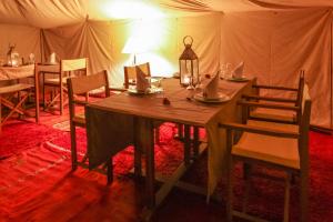 - un tavolo e sedie in legno in tenda di Bivouac de Luxe Le Pacha a M'Hamid
