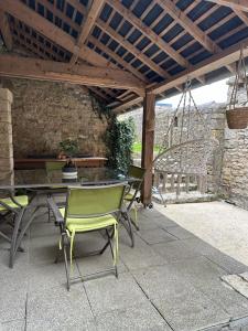a patio with a table and chairs and a swing at La maison des lauriers in Valognes
